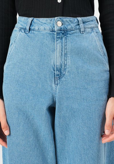 Lichtblauwe high-waisted jeans van denim, voorzien van een voorste knoop, twee zijzakken en een relaxte pasvorm met een subtiele textuur.