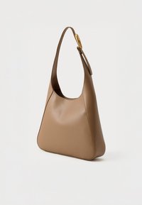 Pruun nahast õlakott kumerate käepidemete ja kuldsete detailidega. Kotil on sile pind ja asümmeetriline kuju.