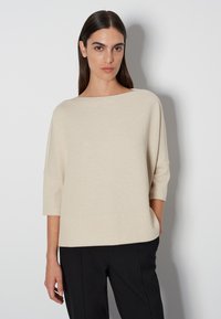 Beiger Strickpullover mit weitem Ausschnitt, Dreiviertelärmeln und lässiger Passform. Der Stoff hat einen dezenten Glanz und eine glatte Textur.