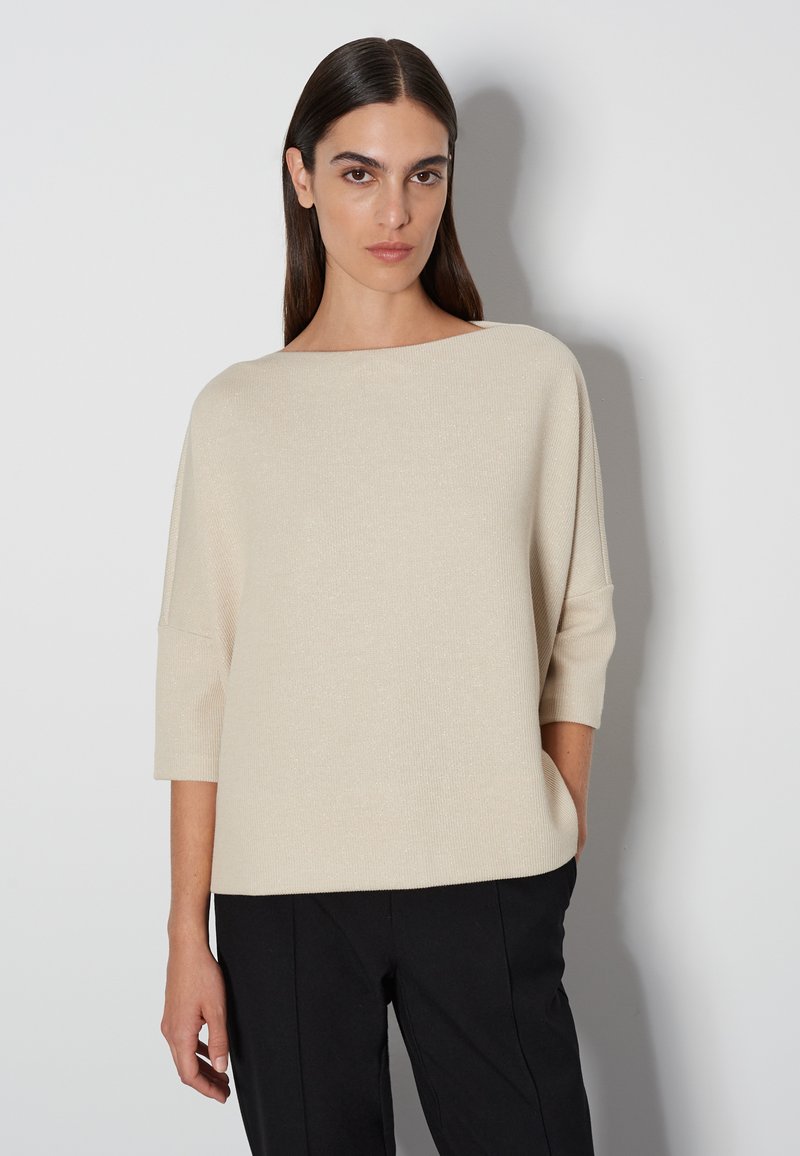 Beiger Strickpullover mit weitem Ausschnitt, Dreiviertelärmeln und lässiger Passform. Der Stoff hat einen dezenten Glanz und eine glatte Textur.