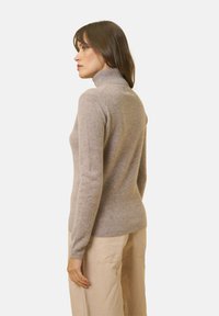 Hellsilberner, hochgeschlossen Pulli aus weichem Material mit figurbetontem Schnitt und langen Ärmeln. Er zeichnet sich durch eine glatte Textur und minimale Nähte aus.