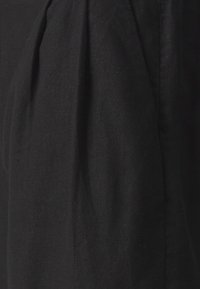 Tissu noir avec des plis verticaux subtils et une texture de lin visible en gros plan.