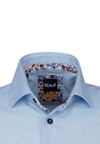 Camicia in cotone blu chiaro con una vestibilità moderna. Presenta un motivo floreale sul colletto interno e un bottone scuro al collo.