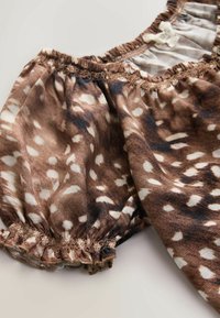 Tissu transparent brun et blanc à pois avec fronces élastiques à l'ourlet et à l'encolure, ressemblant à une manche légère de blouse.