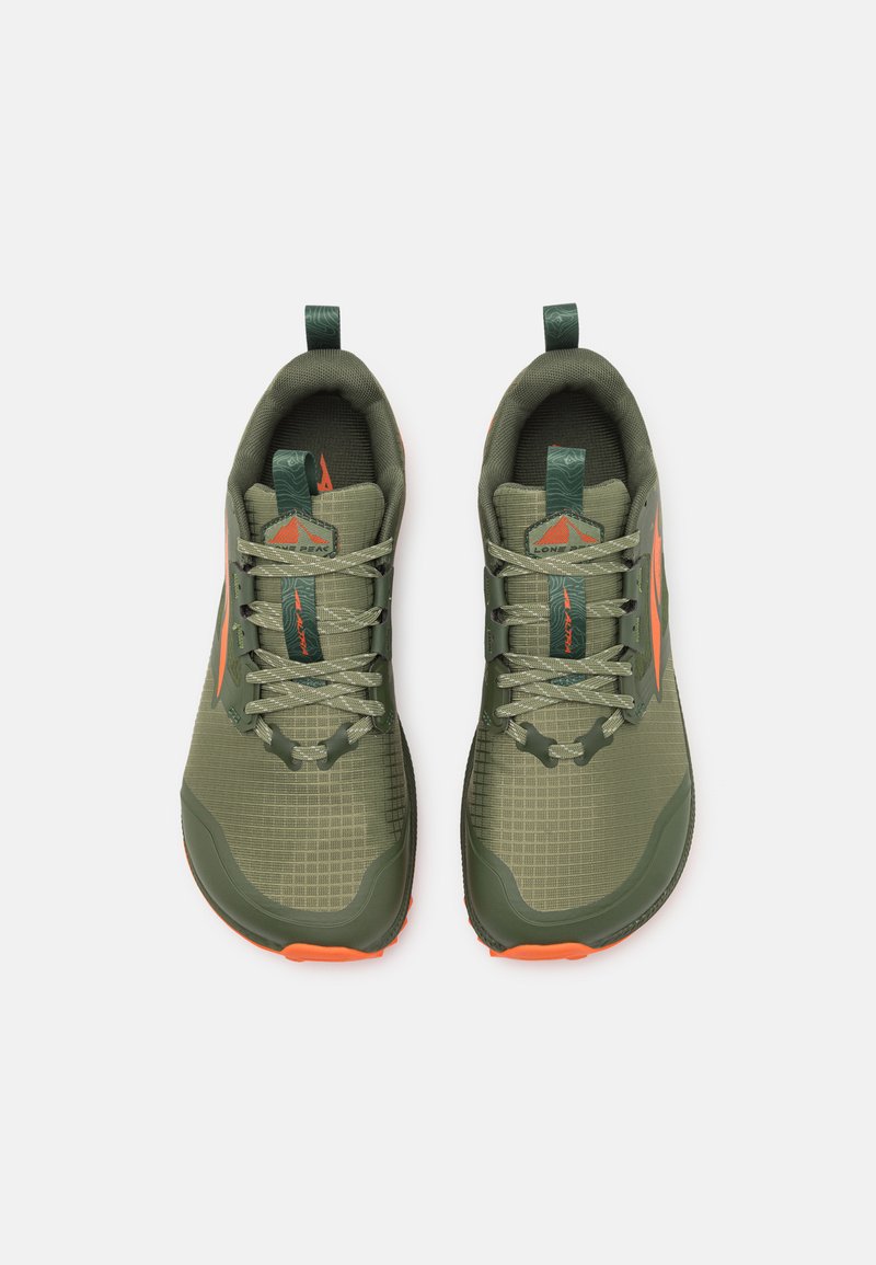 Zapatillas deportivas verdes con parte superior de malla texturizada, acentos naranjas y una suela acolchada. Las características incluyen un tirador en el talón y cordones entrelazados.