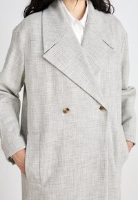 Grijs geruit dubbelzijdig jasje met grote revers, gemaakt van textiel met een structuur en gouden knopen, ontworpen met zijzakken.