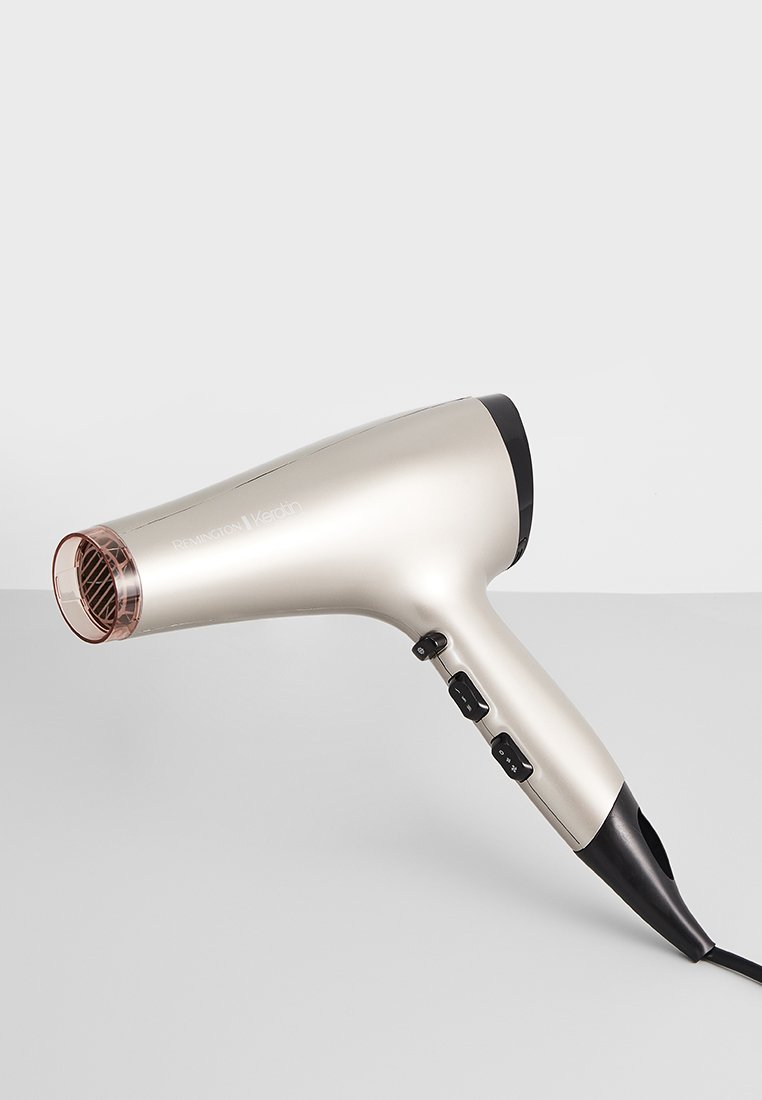 Sèche-cheveux Remington Keratin avec un design noir et or métallique, doté d'une poignée texturée, de plusieurs boutons de contrôle et d'une grille en or rose.