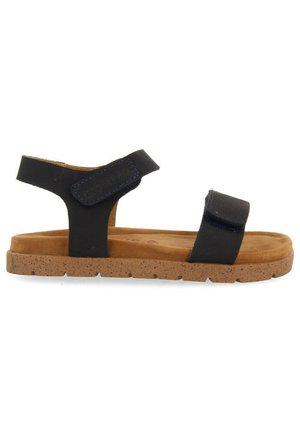 Sandalias negras con dos tiras de Velcro ajustables, suela de corcho y plantilla acolchada en color tostado. Diseño minimalista y perfil plano.