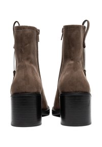 Stivaletti alla caviglia in suede marrone con una texture liscia, caratterizzati da un tacco a blocco nero, una cerniera posteriore e un'asola per facilitare la calzata.