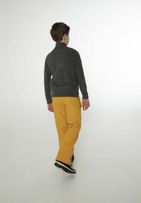 Pullover in pile grigio scuro, abbinato a pantaloni gialli. Il pullover ha un col alto, e i pantaloni presentano una tasca laterale e una vestibilità comoda.