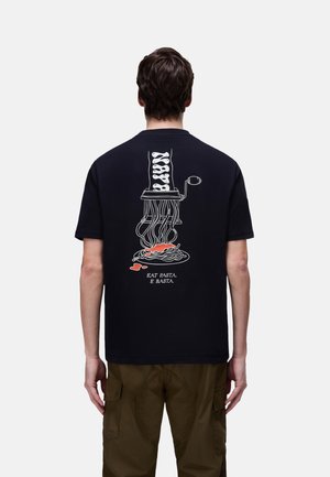 Persona che indossa una maglietta nera con grafica bianca di una macchina per la pasta e salsa rossa, il testo sotto dice "MANGIA LA PASTA. E BASTA."