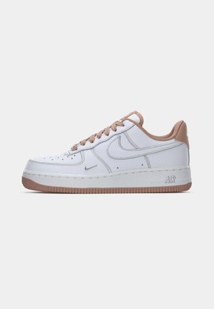 White leather sneaker with a smooth texture, beige accents, low top design, and rubber outsole featuring grooves for traction.