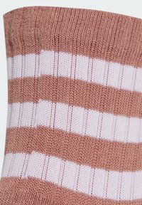 Calcetines a rayas rosa claro y blancos con una textura acanalada. El diseño cuenta con secciones alternas sólidas y a rayas, fabricadas con un material suave.