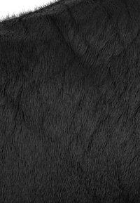 Pelliccia artificiale nera con una texture morbida e densa, caratterizzata da lunghe ciocche e un leggero motivo ondulato sulla superficie.