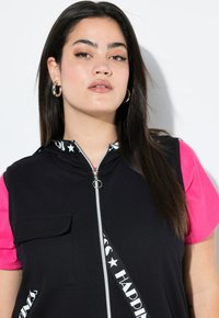 Schwarze Zip-Up-Weste mit Kapuze, kontrastierenden pinken kurzen Ärmeln, Fronttasche und detailliertem Riemen mit dem Text "HAPPINESS" und Sternmotiven.