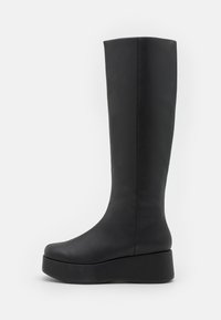 Botas negras hasta la rodilla con un acabado de cuero sintético suave, punta redondeada y una suela de plataforma gruesa para mayor altura y estabilidad.