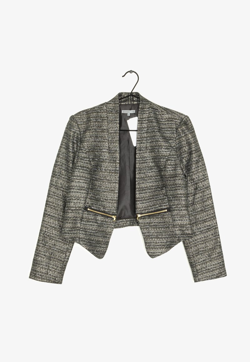 Blazer court texturé gris et noir pour femme avec manches longues, devant ouvert et deux poches zippées dorées suspendu à un cintre noir.