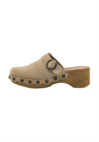 Zueco de ante beige con punta redonda, bordes festoneados y tachuelas decorativas de metal oscuro a lo largo de la suela; tacón de madera y correa con un detalle de hebilla.