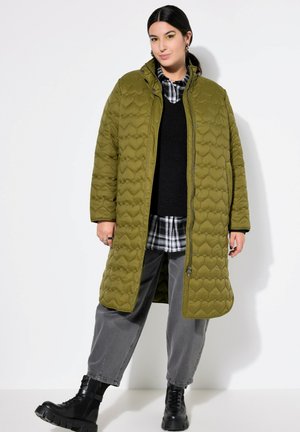 Olive green quilted coat with a high collar, featuring a puffy design and heart-shaped pattern, layered over a black sweater and plaid shirt.