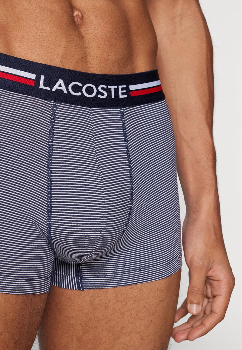 Marineblaue gestreifte Boxershorts mit elastischem Bund und Logo, ausgestattet mit feinen weißen und roten Balkenakzenten. Weicher Stoff mit eng anliegender Passform.