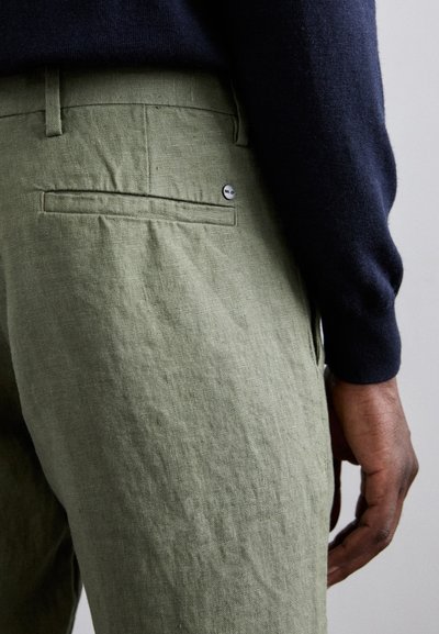 Olijf groene linnen broek met een achterzak, voorzien van een kleine zilveren logo-knop. Gelaagd stof met een licht gekreukeld uiterlijk.