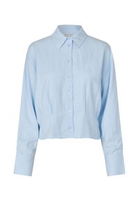 Světle modrá zkrácená košile na knoflíky vyrobená z lnu. Má klasický límec, dlouhé rukávy a jemné šicí detaily na přední straně.