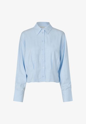 Lys blå kort knappeskjorte laget av lin. Har klassisk krage, lange ermer og subtile sømdetaljer foran.