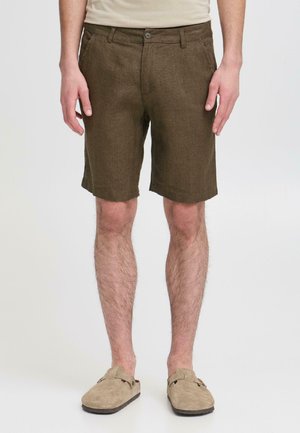 Roze linnen korte broek met een gestructureerde afwerking, een platte voorkant, zijzakken en een enkele knoopsluiting. Draagt beige instapschoenen.