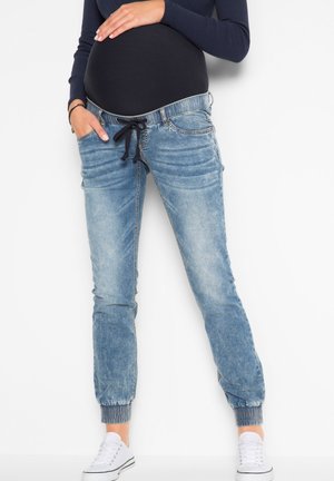 Jean de maternité en denim bleu clair, avec taille à cordon, poches latérales et poignets côtelés pour le confort et la facilité.