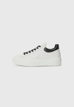 Sneakers bianchi in pelle con accenti neri, punta rotonda e suola spessa e texturizzata. Presenta lacci neri e dettaglio del logo sul lato.