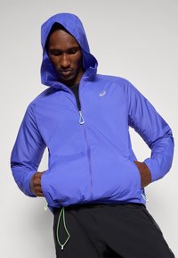 Kerge, lilla jope kapuutsiga, esilukuga ja elastsete nööridena allääres. Sile tekstuur ja logo aktsent.