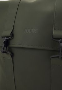 Sac imperméable vert olive avec finition mate, doté de matériel noir, de bretelles ajustables et du logo "RAINS" en relief à l'avant.