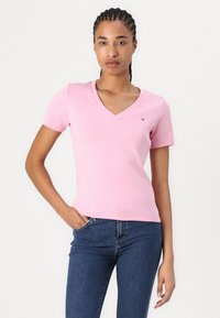 Pink short-sleeve V-neck t-shirt with a fitted design. Features a small logo on the chest and soft, stretchy cotton material.