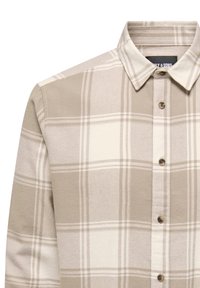 Beige rutete skjorte med lange ermer, med hvite og lysebrune linjer. Den har krage med knapper og brune knapper foran.