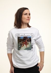 Sudadera blanca con un gráfico rectangular de un patinador, rodeado de texto estilizado. Tela suave, corte relajado, puños acanalados.