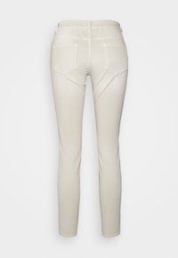 Jeans beige ajustados con una textura suave, que cuentan con bolsillos traseros, una cinturilla estándar y un diseño de pierna recta.