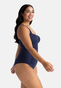 Mornarsko enodelno kopalo z nabrano obdelavo, nastavljivimi naramnicami in srčastim izrezom, izdelano iz gladkega, raztegljivega blaga.