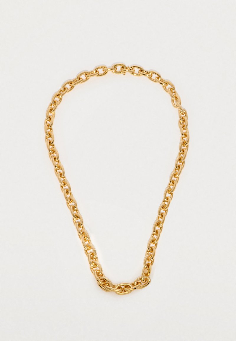 Zlata verižica z ovalnimi srednje velikimi povezovalnimi članki, položena ravno na preprosto belo ozadje.