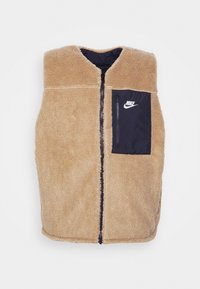 Beige fleeceväst med hög krage, zippered front och en svart dragkedjeficka med Nike-logotypen på vänster sida. Texturerad yta.