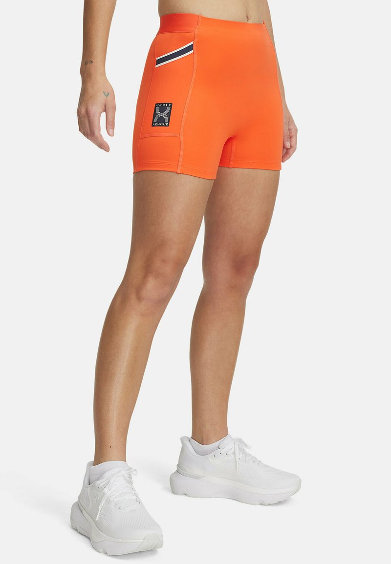Oranje sportshorts met een nauwsluitende pasvorm, voorzien van een zwart-witte streepaccent en een merkpatch aan de zijkant. Gladde textuur.