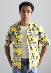 Cămașă galbenă cu mânecă scurtă, decorată cu un imprimeu tropical cu palmieri și flori. Fabricată dintr-un material ușor, cu un croi lejer.