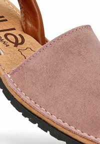 Sandalia de ante rosa con parte superior redondeada, correa de cuero, plantilla texturizada con marca y suela de goma negra en contraste.