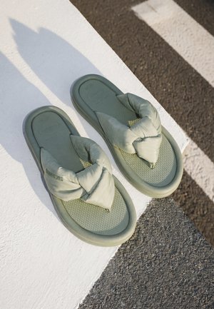 Egy pár zöld párnázott flip-flop fekete-fehér csíkos gyalogátkelőhelyen, aszfaltburkolaton.