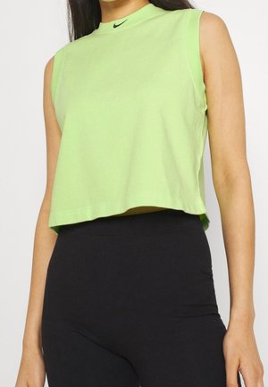 Top corto sin mangas de color verde claro hecho de algodón, con un escote alto y el logo negro de Nike en el cuello. Textura lisa.