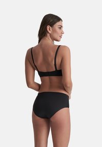 Set di bikini nero con design semplice, spalline regolabili e chiusura posteriore a gancio. Il tessuto è liscio e leggermente lucido.