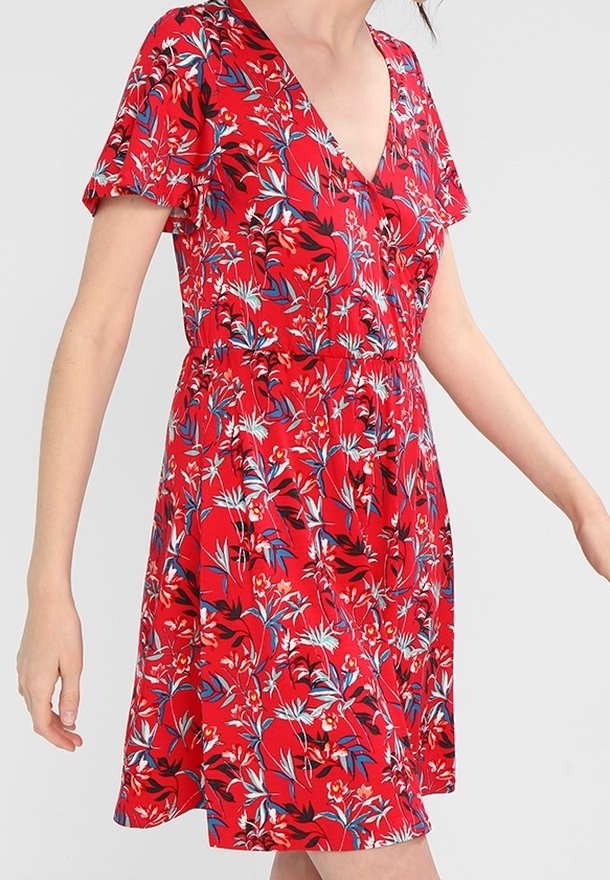 Czerwona sukienka w kwiaty z krótkimi rękawami, dekoltem w kształcie litery V i rozkloszowanym dołem, ozdobiona białymi i niebieskimi wzorami kwiatów oraz zielonymi akcentami liści.