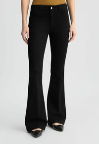 Zwarte uitlopende jeans met een vijf-pocket ontwerp, voorzien van een knoopsluiting aan de voorkant en een lichte stretch voor comfort. Glad textuur, klassieke pasvorm.