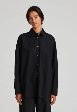 Black button-up shirt with a collar, long sleeves, patch pocket, and a relaxed fit, made from a smooth, lightweight fabric.