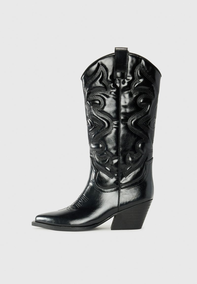 Bota de cowboy em couro preto com bico pontudo, costura decorativa e salto angulado. Apresenta uma textura suave e acabamentos elevados.