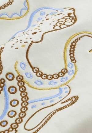 Kirjailtu mustekalakuosi, jossa ruskeita, sinisiä ja keltaisia lankoja vaalealla kermaisella kankaalla, yksityiskohtaisilla kiepireillä ja pyöreillä kuvioilla.